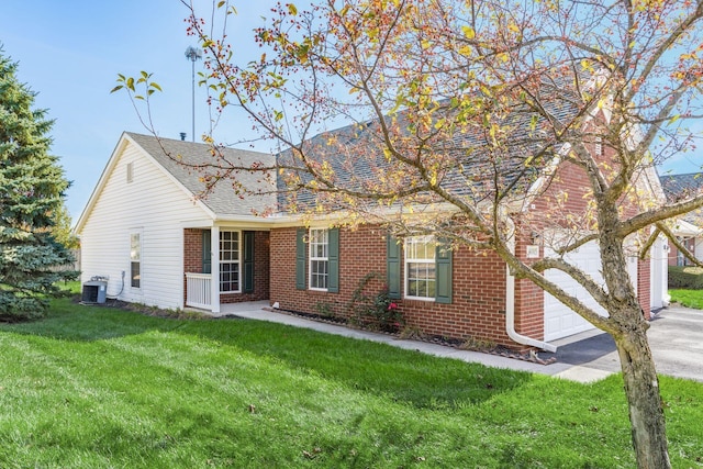 view of front of property with a garage, central AC, brick siding, driveway, and a front lawn