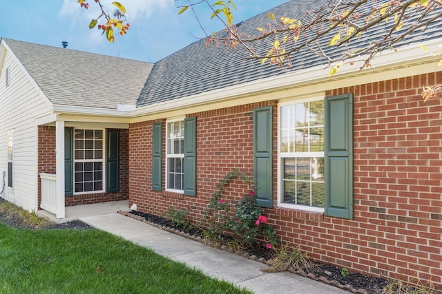 property entrance with a shingled roof and brick siding