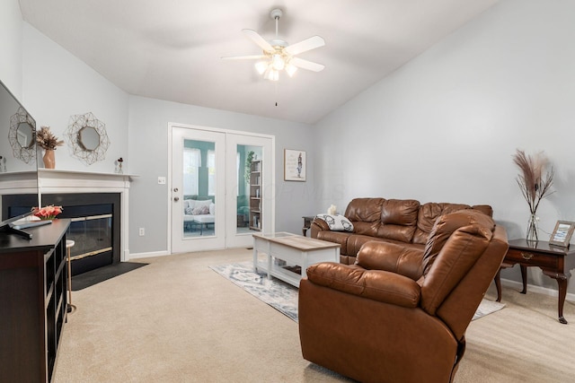 living room with baseboards, a ceiling fan, lofted ceiling, a fireplace with flush hearth, and carpet flooring