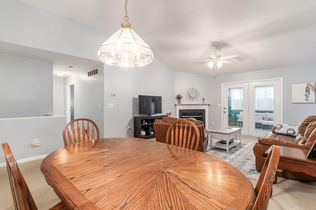 carpeted dining space featuring baseboards, a fireplace, visible vents, and ceiling fan with notable chandelier