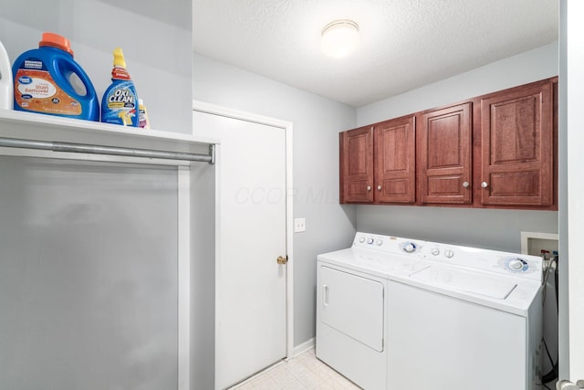 washroom featuring cabinet space, light floors, a textured ceiling, and washing machine and clothes dryer