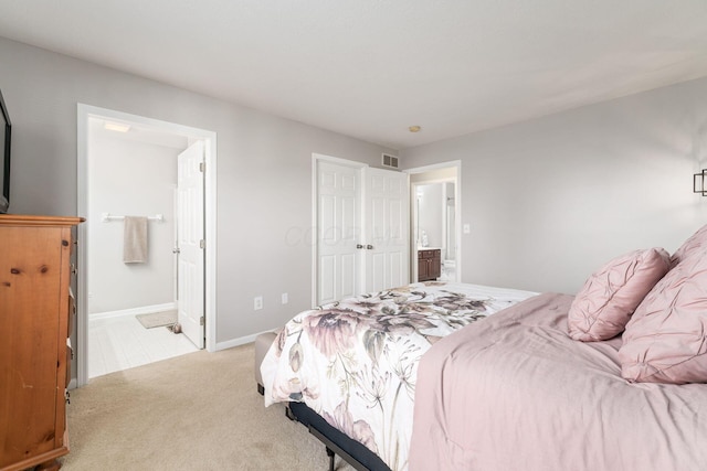 bedroom with light carpet, visible vents, baseboards, and ensuite bathroom