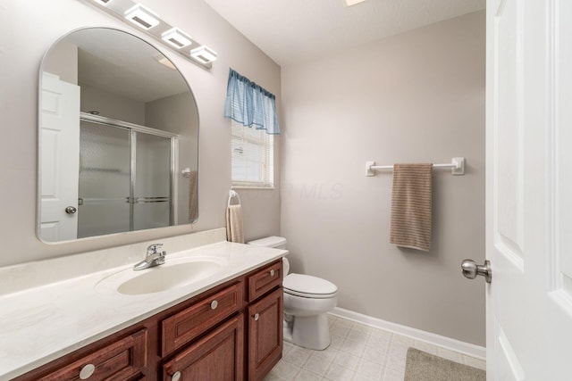 bathroom featuring toilet, a shower stall, vanity, baseboards, and tile patterned floors