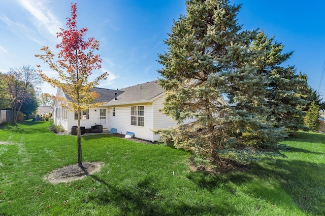 rear view of property featuring a lawn and central air condition unit