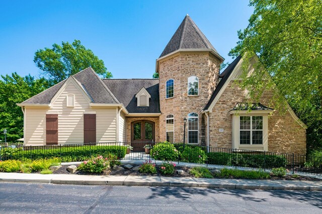 view of front of house featuring a fenced front yard, stone siding, and roof with shingles