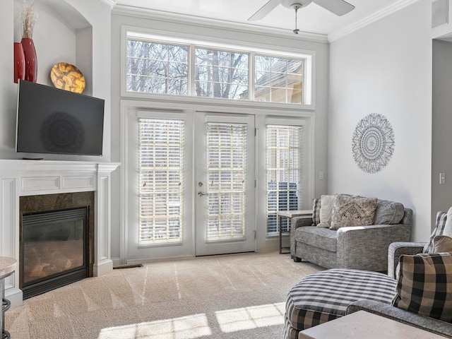 carpeted living room with ceiling fan, french doors, ornamental molding, and a high end fireplace