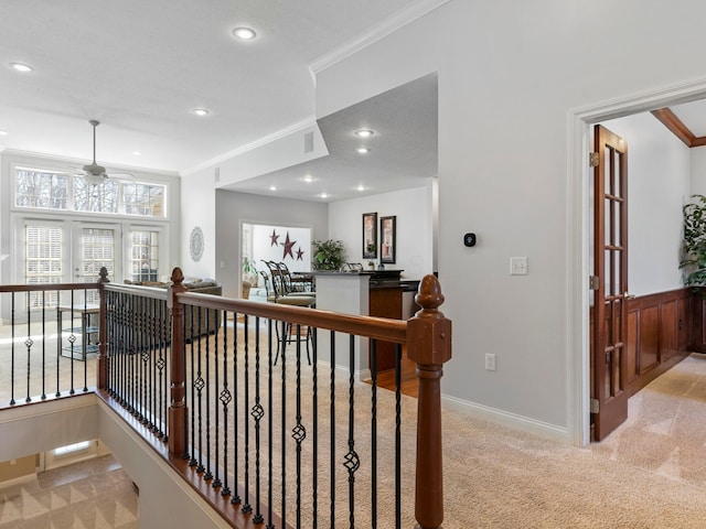 hallway featuring an upstairs landing, light carpet, and ornamental molding