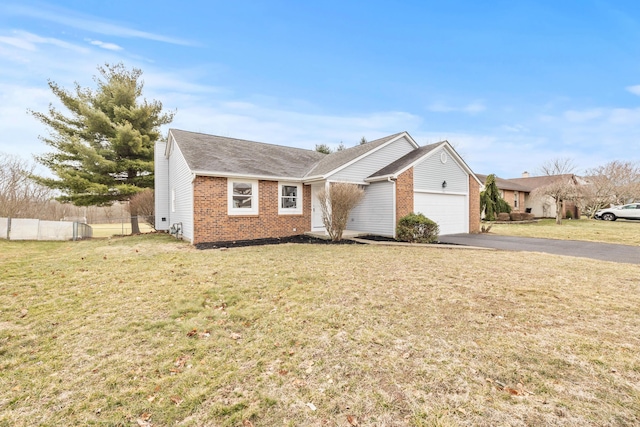 view of front facade featuring fence, driveway, a front lawn, a garage, and brick siding