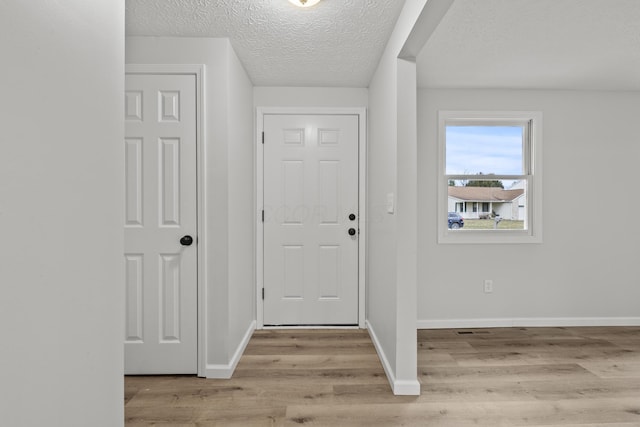 entrance foyer featuring baseboards, light wood-type flooring, and a textured ceiling