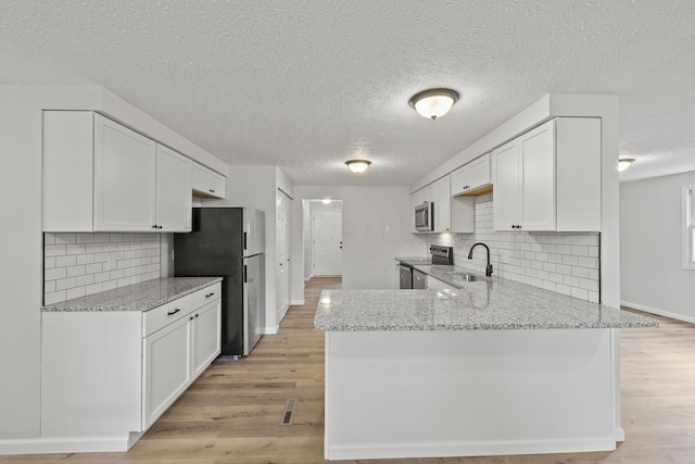 kitchen with white cabinetry, light wood-style floors, appliances with stainless steel finishes, and a sink