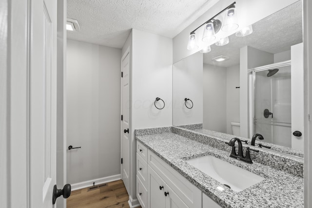 full bath with visible vents, toilet, a stall shower, wood finished floors, and vanity