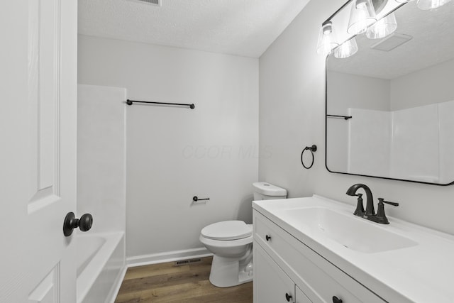 bathroom featuring vanity, toilet, wood finished floors, and a textured ceiling