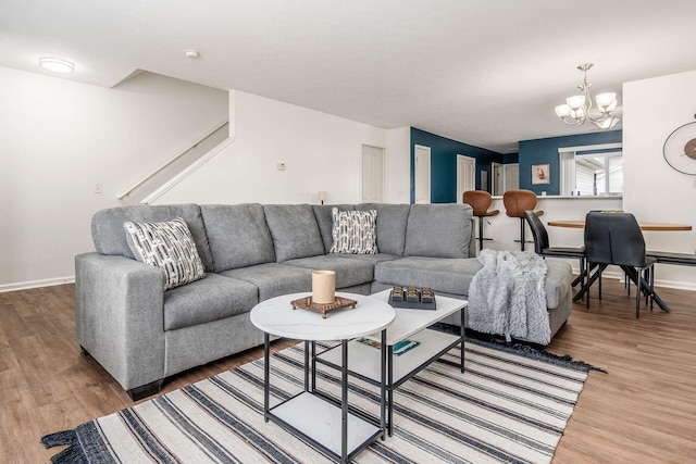 living room with baseboards, wood finished floors, and a notable chandelier