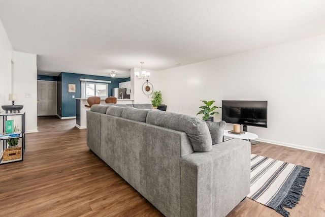 living area featuring baseboards, a chandelier, and wood finished floors