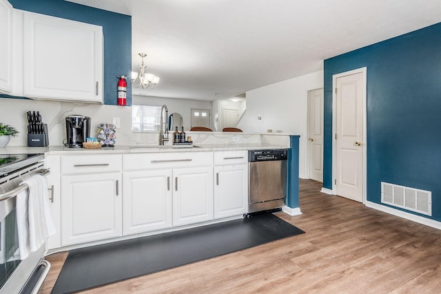 kitchen with visible vents, light wood-style flooring, appliances with stainless steel finishes, a sink, and a peninsula