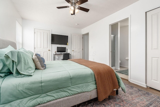 bedroom with baseboards, ensuite bath, a ceiling fan, and wood finished floors