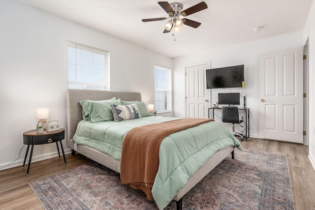 bedroom with ceiling fan, light wood-style flooring, and baseboards