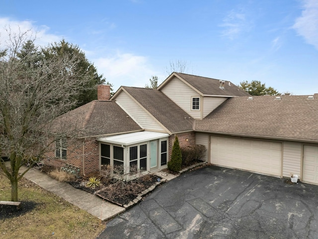 view of front of home with driveway, a shingled roof, a garage, and brick siding