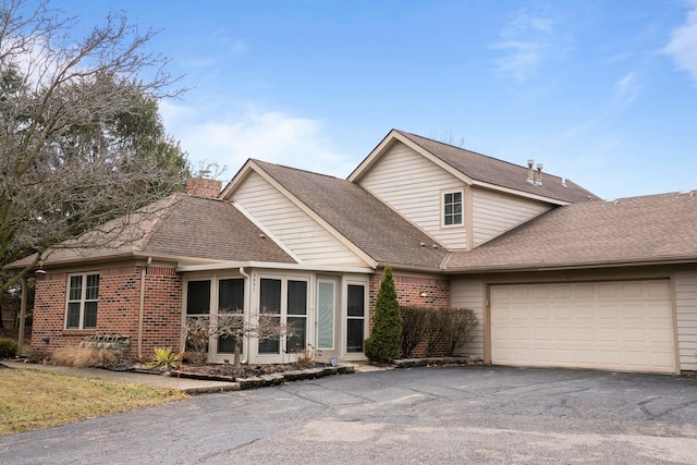 view of front of property featuring a garage, driveway, roof with shingles, and brick siding