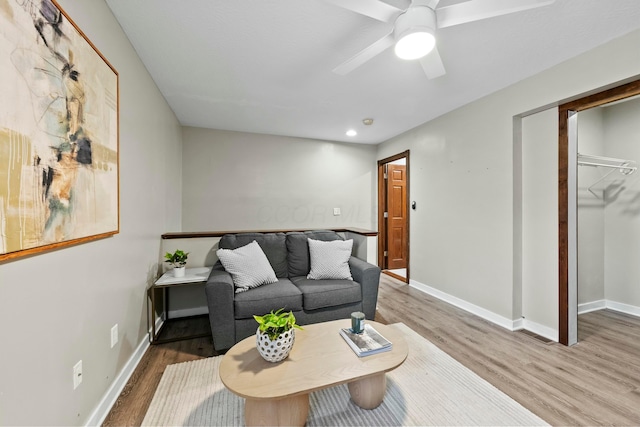 living area featuring ceiling fan, baseboards, and wood finished floors