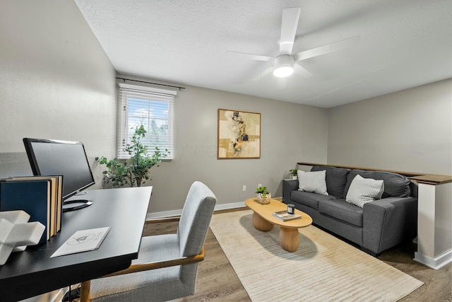 home office featuring ceiling fan, a textured ceiling, baseboards, and wood finished floors