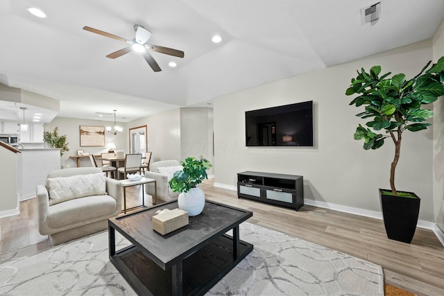 living area with recessed lighting, light wood-style flooring, baseboards, and ceiling fan with notable chandelier