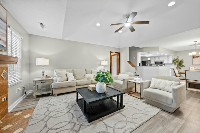 living area featuring recessed lighting, ceiling fan with notable chandelier, baseboards, vaulted ceiling, and light wood-type flooring