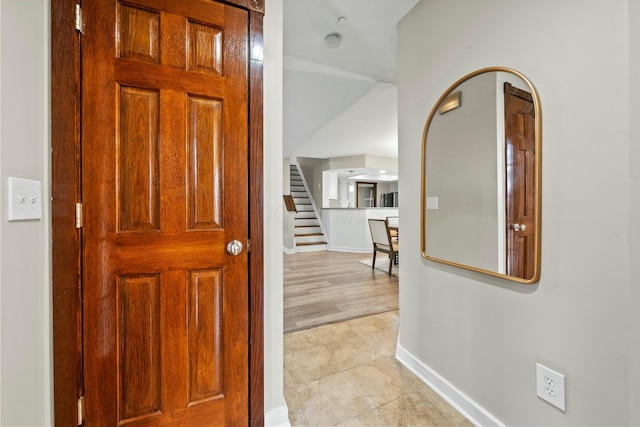 hall featuring light tile patterned floors, stairway, and baseboards