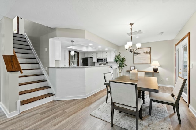 dining room featuring visible vents, stairway, an inviting chandelier, light wood-style floors, and baseboards