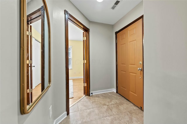 hall with light tile patterned floors, baseboards, and visible vents