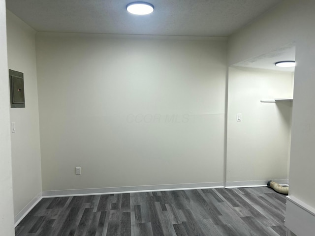 unfurnished room featuring dark wood-style floors, electric panel, and baseboards