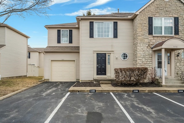 view of property featuring uncovered parking and stone siding