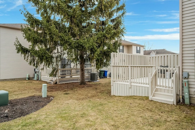 view of yard with central AC unit, a wooden deck, and fence