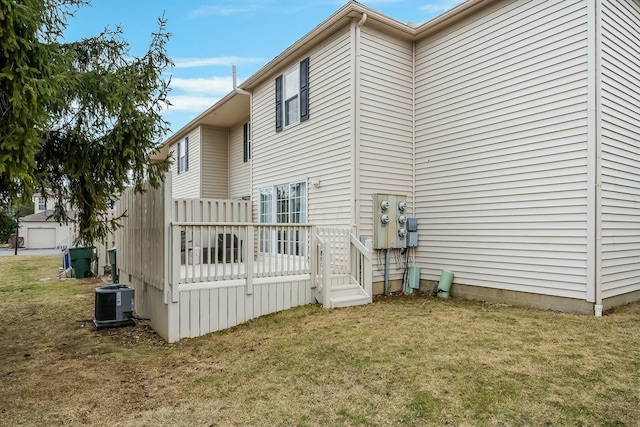 view of side of property with a wooden deck, central AC unit, and a yard