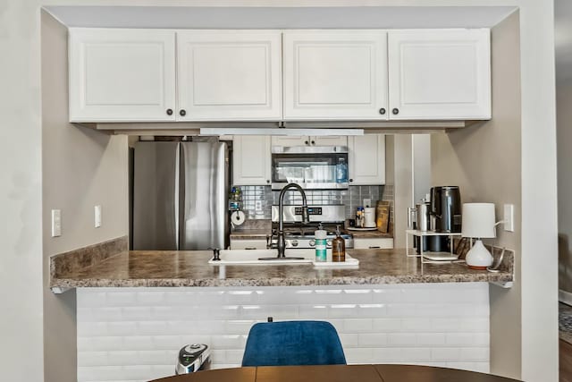 kitchen featuring stainless steel appliances, white cabinets, a peninsula, and tasteful backsplash