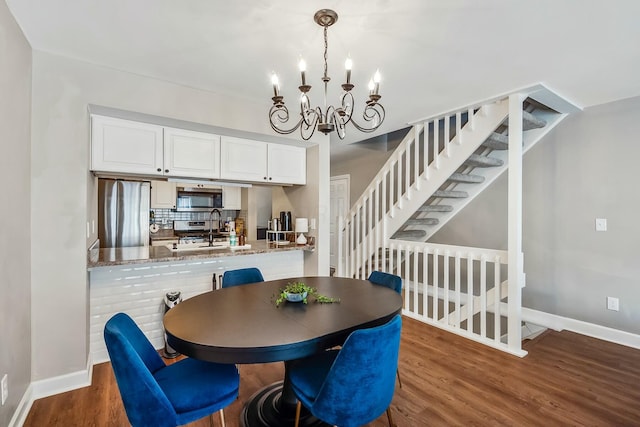 dining room featuring baseboards, stairway, a chandelier, and wood finished floors