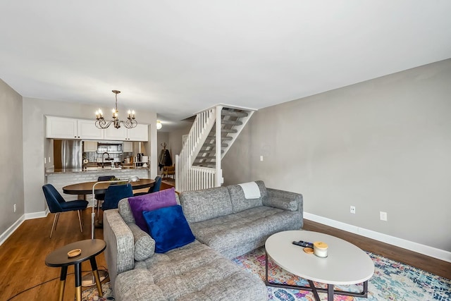 living area with baseboards, stairs, a chandelier, and dark wood-style flooring