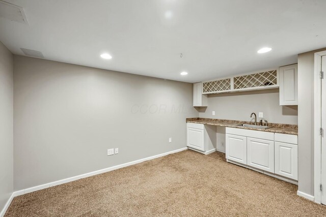 kitchen featuring recessed lighting, light carpet, a sink, and baseboards