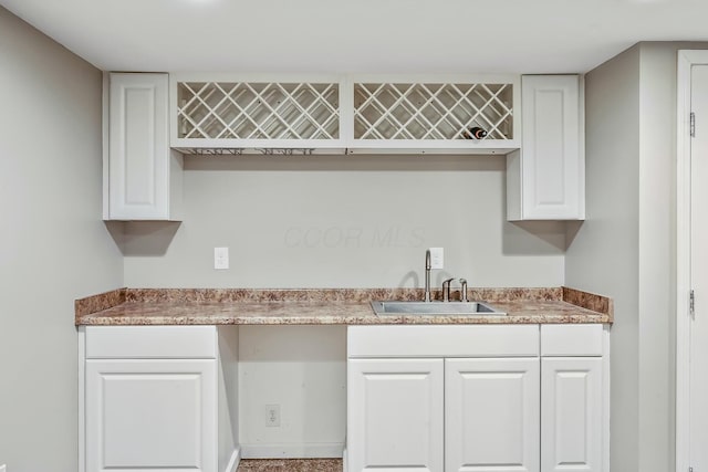 kitchen with baseboards, light countertops, a sink, and white cabinets