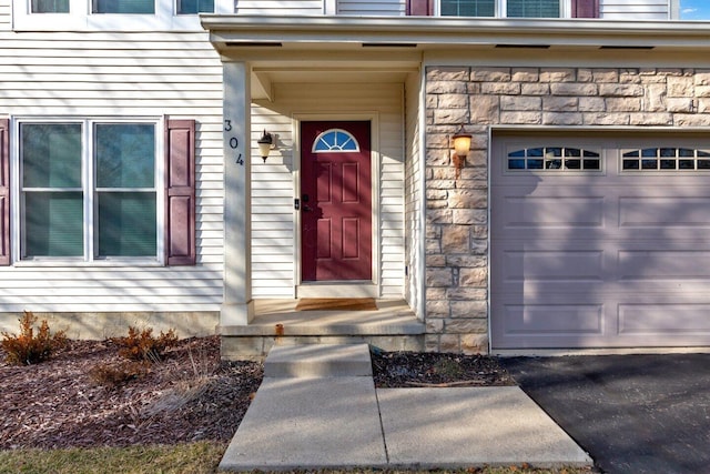 property entrance with a garage and stone siding