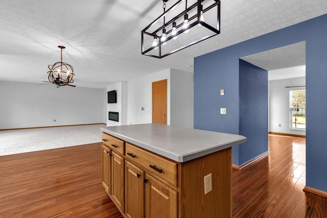 kitchen with open floor plan, a fireplace, a kitchen island, and dark wood-style floors