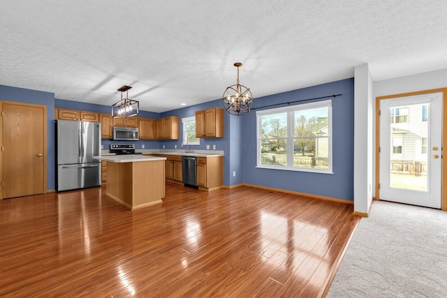 kitchen with an inviting chandelier, appliances with stainless steel finishes, light countertops, and wood finished floors