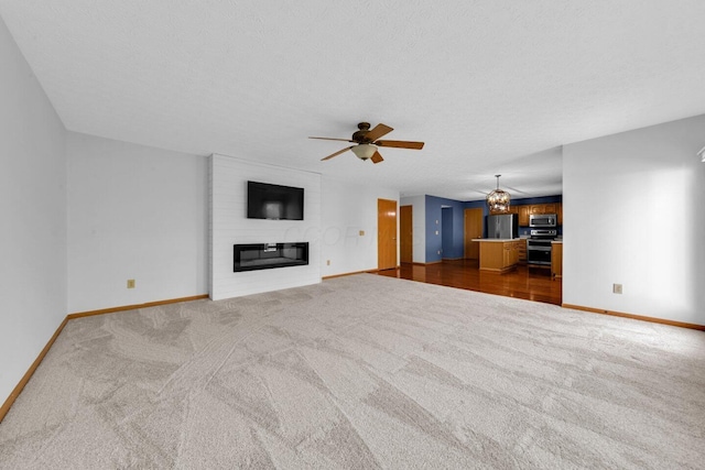 unfurnished living room featuring dark colored carpet, a fireplace, a textured ceiling, and baseboards