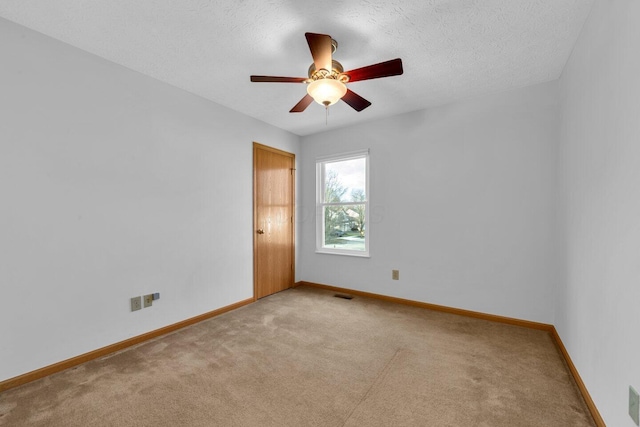 unfurnished room featuring a textured ceiling, light colored carpet, a ceiling fan, baseboards, and visible vents