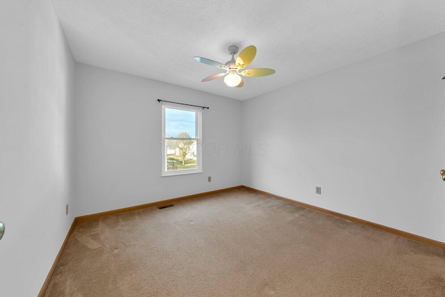 carpeted empty room with visible vents, ceiling fan, a textured ceiling, and baseboards