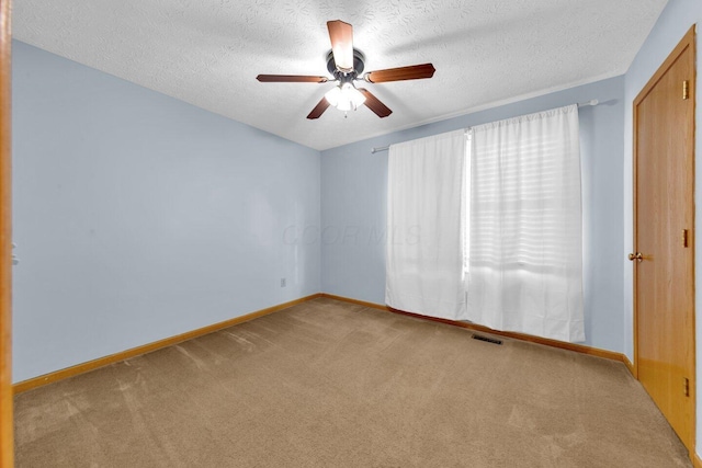 empty room with baseboards, a textured ceiling, visible vents, and carpet flooring