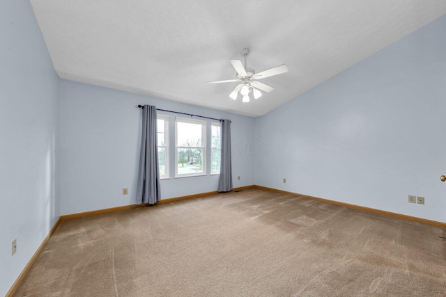 spare room featuring a ceiling fan, carpet flooring, vaulted ceiling, a textured ceiling, and baseboards