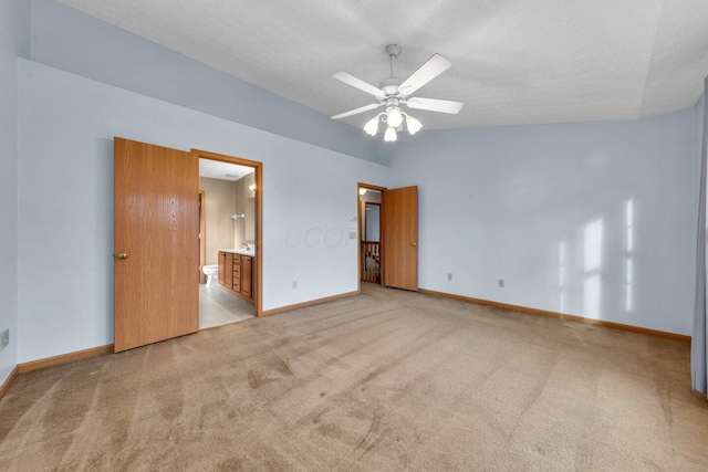 unfurnished bedroom featuring lofted ceiling, a textured ceiling, carpet, and baseboards