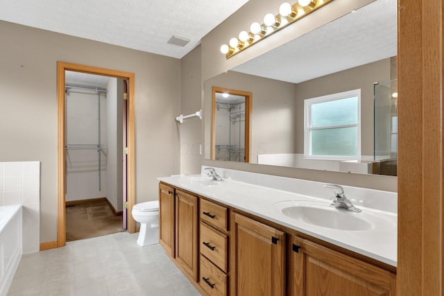 bathroom featuring a garden tub, a textured ceiling, visible vents, and a sink