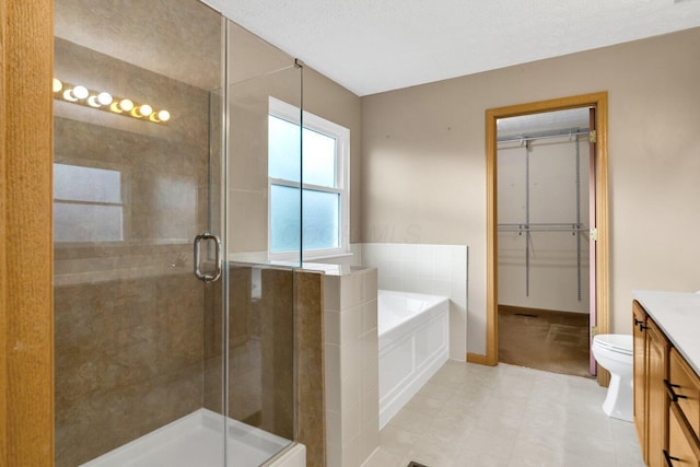 bathroom featuring a garden tub, a shower stall, a spacious closet, and vanity